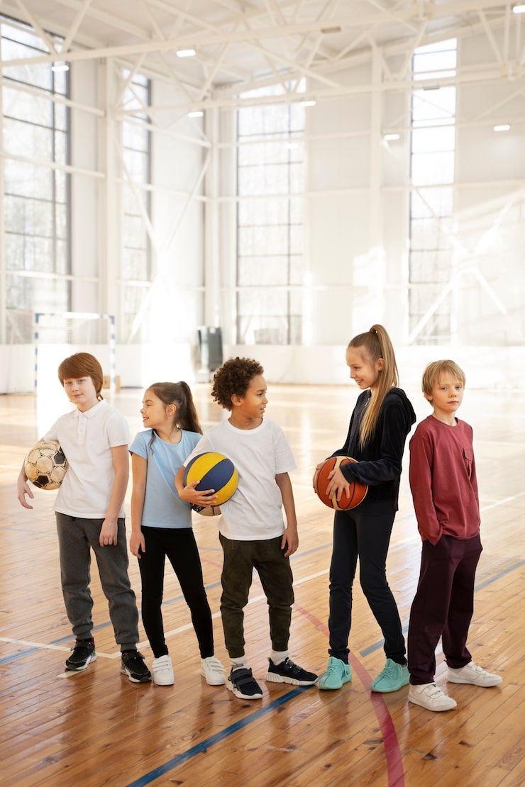 full-shot-children-holding-balls-gym_23-2149351799